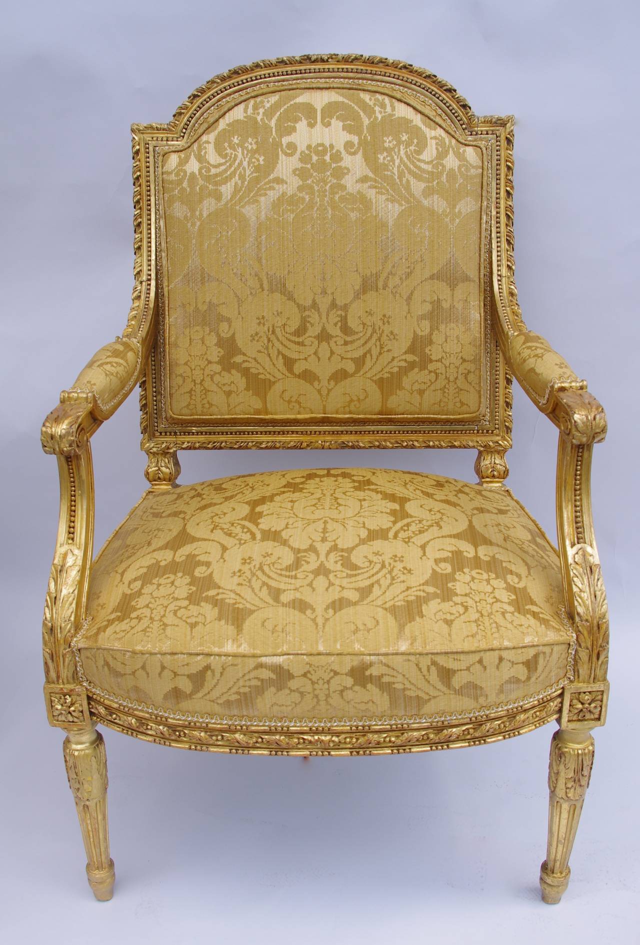 . Louis XVI style
. Carved and giltwood
. On tapering tapered and fluted legs
. Leaf-wrapped arms on piastre-carved supports
. Terminating in toupie feet