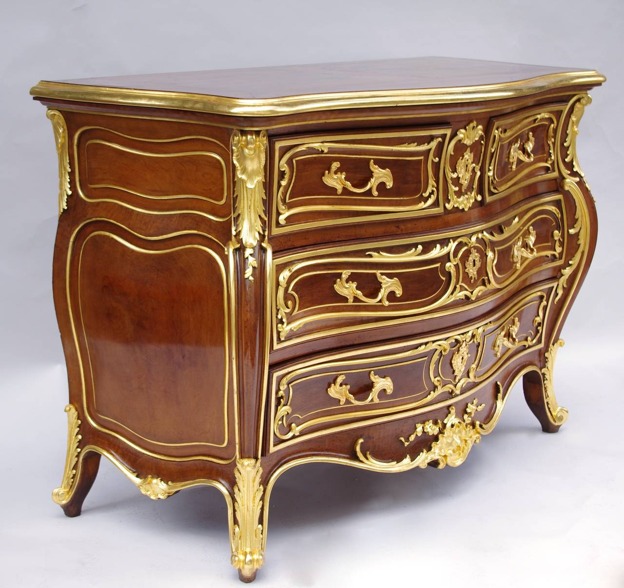 Louis XV style walnut tomb shaped commode opening with four drawers on three levels.  Chantourné uprights, crossbow shaped apron, standing on four small curved legs.
Gilt highlights such as acanthus leaves on angles, lingotière or net framing the