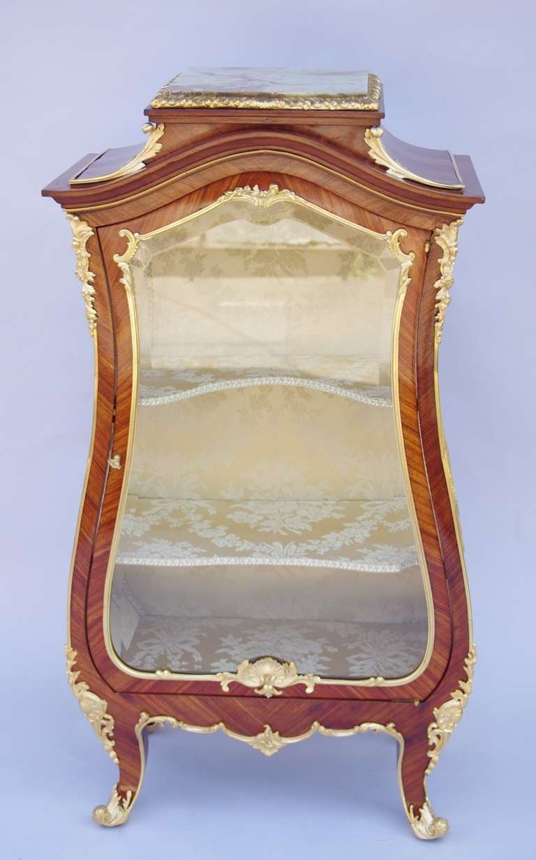 Marquetry, Louis XV style. Gilt bronze, onyx top. Opening on one door with two shelves. Belleved glass. French work from the end of the 19th century.