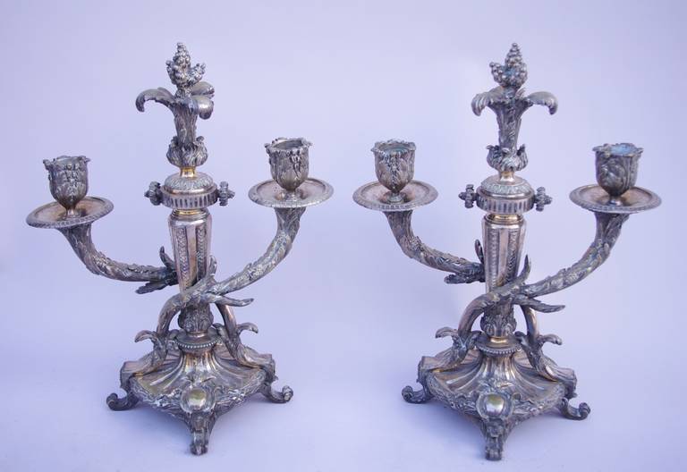 Pair of Louis XVI style two fires candleholders in chiseled and silvered plate. Oval tapered base standing on four decorated with a laurel wreath torus and cartouches. Central structure in baluster shape adorned with acanthus leaves, tapering, water