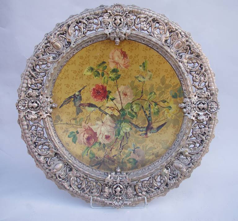 Large ornamental plate composed of a round picture in enamelled iron representing birds in a rose tre framed by an openwork wrought iron with interlacing decoration of plants and a gadroon frieze.
Visible signature in the bottom.
French work made