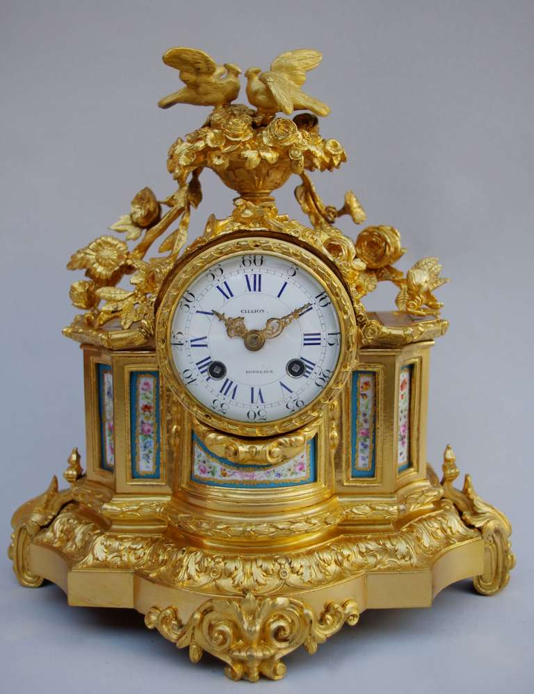 Louis XVI style table clock in chiseled and gilt bronze.
The case is in “architectural drawing” style shape, adorned with porcelain plates decorated with baskets of flowers in white cartouches framed with celeste blue. This special blue is famous;