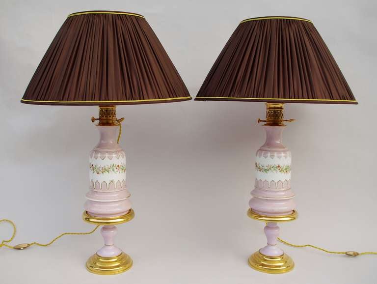 Pair of Lilac colour Paris porcelain lamps standing on a piedouche shape base mounted in gilt bronze. The upper part of the vase is decorated with a white background frieze with a flowery branch on the center and framed with gilt mantlings.
Round