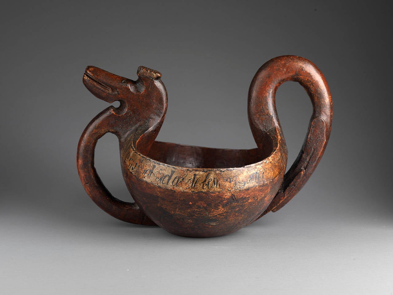 Ceremonial Kasa with stylized dragon’s head and tail incorporating loop handles. 
Hewn and hand-carved birchwood retaining traces of original rosemaling 
with traces of original inscription including the Date “1864.”