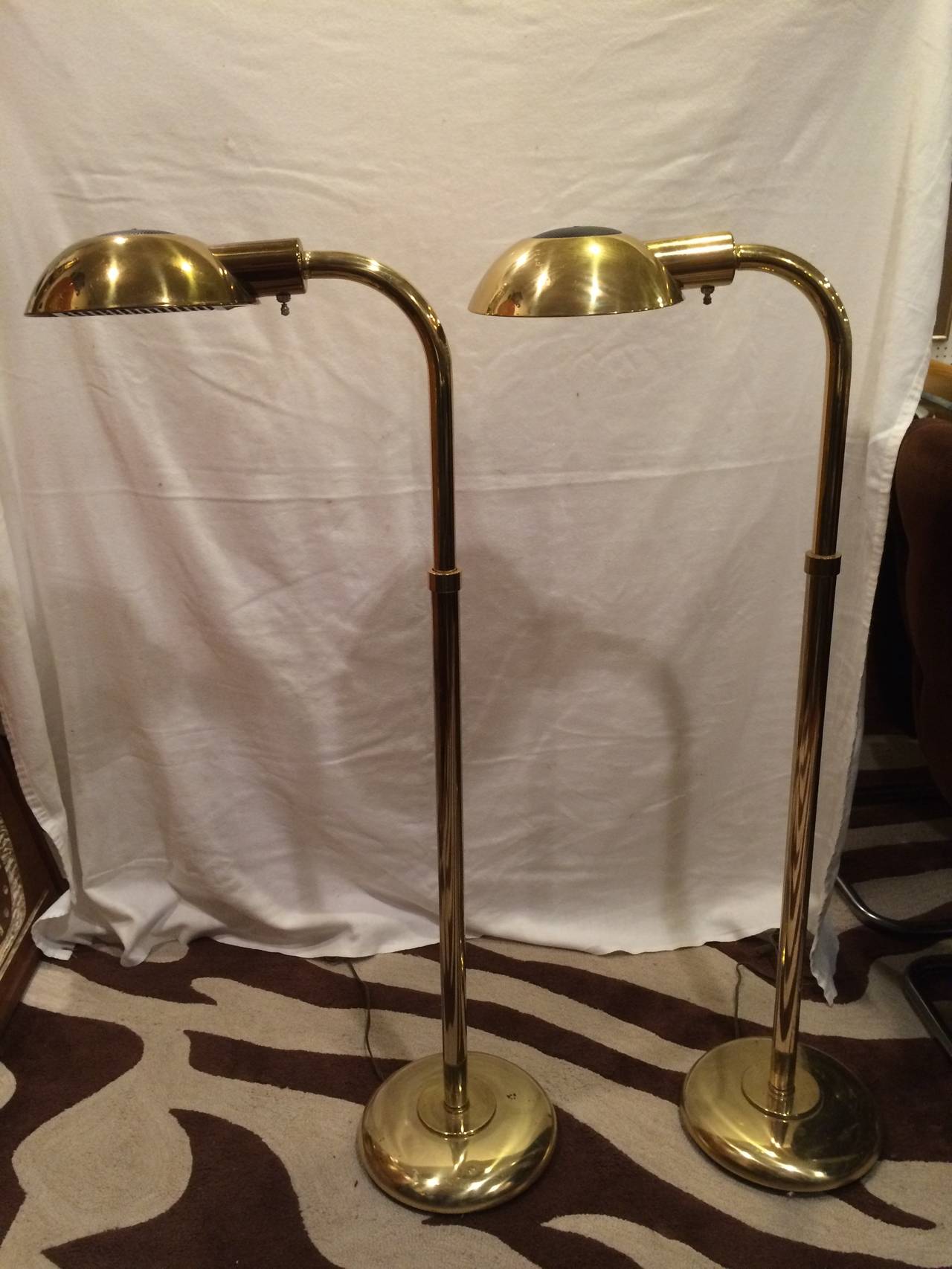 Pair of Mid-Century Modern brass floor lamps.Swiveling adjustable head and neck. Not adjustable in height.