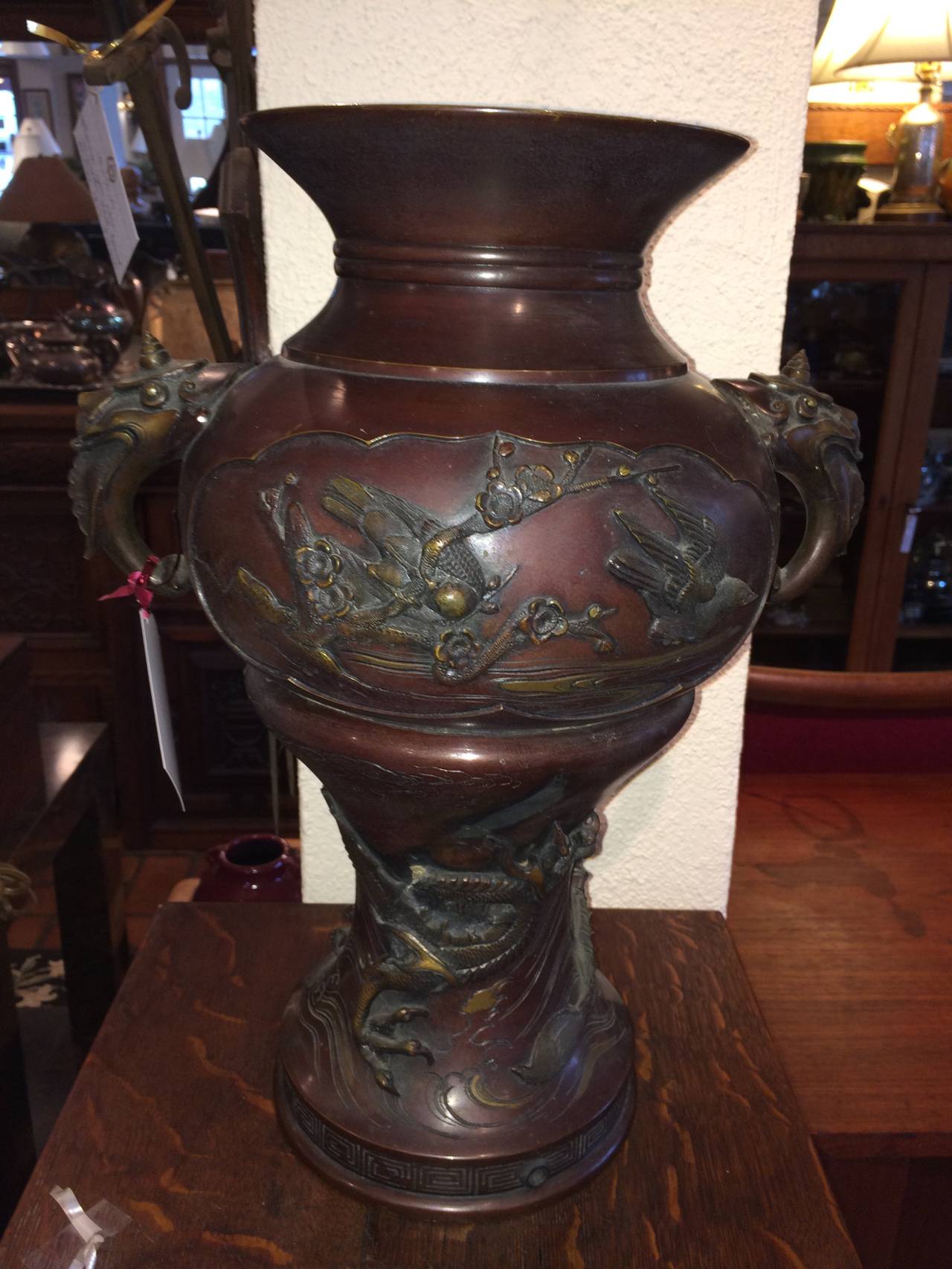 Large Meiji period bronze twin handled urn with decoration. Decoration consists of raised birds, branches with cherry blossoms and a dragon. Nice patina to this gorgeous vase that can also be turned into a lamp. Unfortunately the head of the dragon