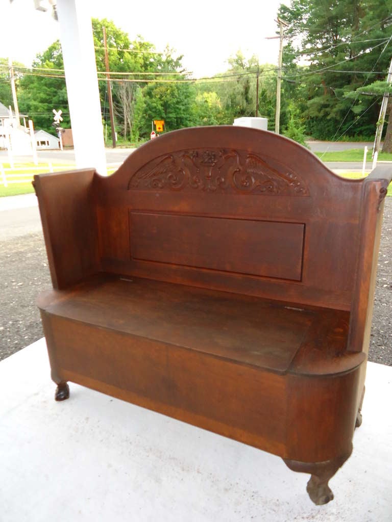 Antique oak settee or hall bench with storage. Seat top flips up to store shoes,hats gloves, etc. Made of quarter sawn oak and embellished with heavy carvings.