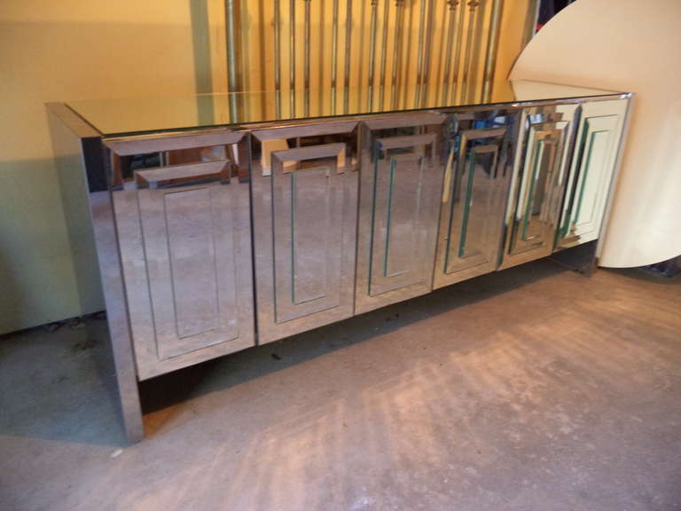 Mirrored six door Credenza by Ello from the Reflections Collection. The sides and trim of this piece are in chrome, enhancing the entire reflection design. The six doors open to reveal a white lacquer interior with three adjustable shelves .  A