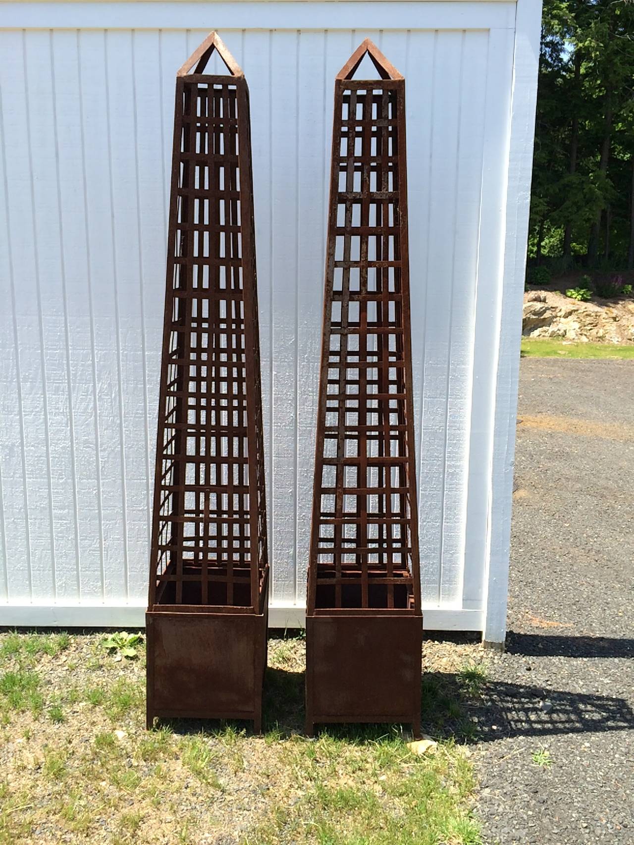 Pair of monumental latticework Iron obelisks with planters. Dramatic for an interior entrance or for a garden or patio. Aged rusted Ironwork. Base planters can be used separately from the trellis obelisk top. Plant a flowering vine and it is