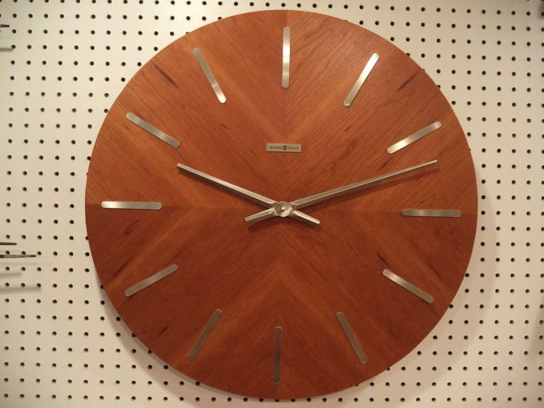 Mid Century Modern Teak Wall Clock by Howard Miller . The hands and digits are made of chrome. The clock is battery operated,  size D battery. It keeps perfect time. The model number is 620-265.George Nelson styling.