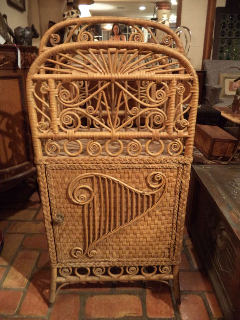 Victorian wicker magazine rack / music stand. Ornately decorated in the manner of Heywood Wakefield. Storage cabinet below with two shelves and magazine or music stand/rack on top. All sides are beautifully decorated.