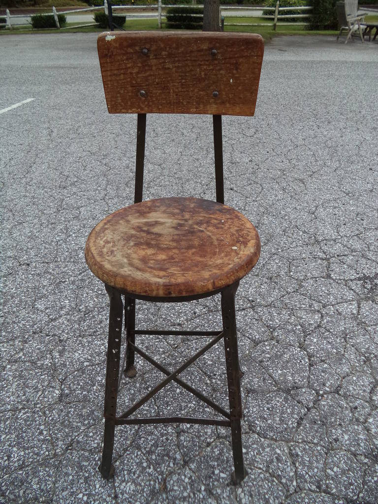 Vintage Industrial stool signed Kalmus Golden of NYC. Nice thick wooden seat and back with heavy iron base. Adjustable height. The stool is 23