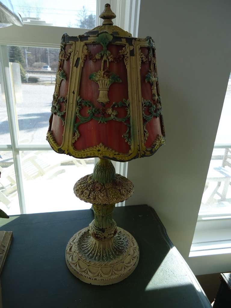 1920s Art Deco Boudoir Lamp with Slag Glass Shade.
Delicate and feminine this lamp is covered with flower baskets, vines and flower buds. The red shade lit up at night makes for very romantic mood lighting.