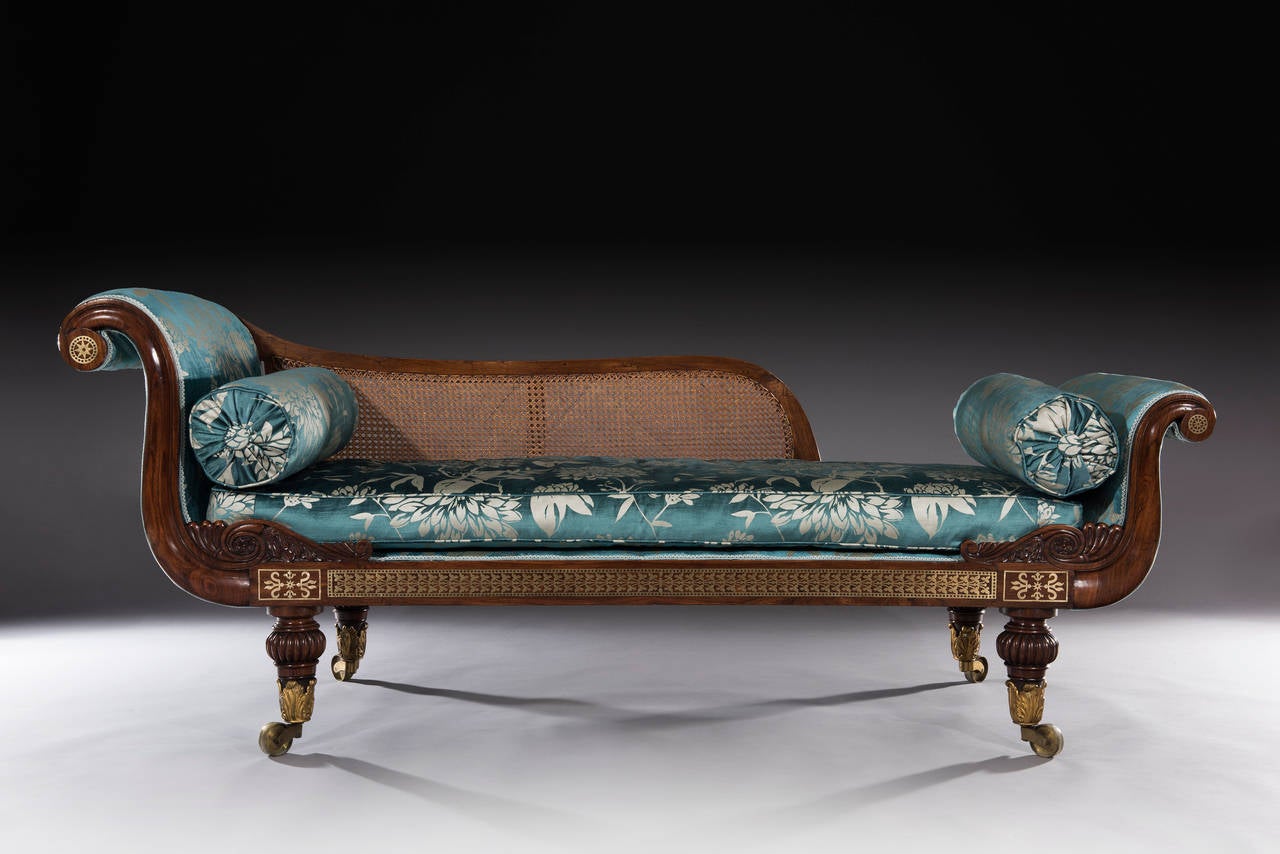 A Regency rosewood brass inlaid sofa in the form of a couch with beautifully figured rosewood veneers and crisply cut brass inlay to the scrolled arms and front rail. The couch sits on four turned rosewood feet, standing on original cast acanthus
