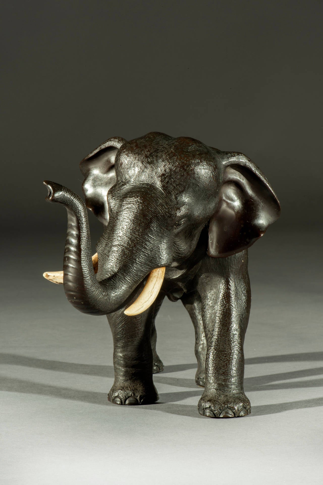 The bull elephant is of rare size and is stamped on the underside of his belly and probably cast and made around the third quarter of the 19th century. Naturalistically striding forward in a majestic pose with original inset ivory tusks.