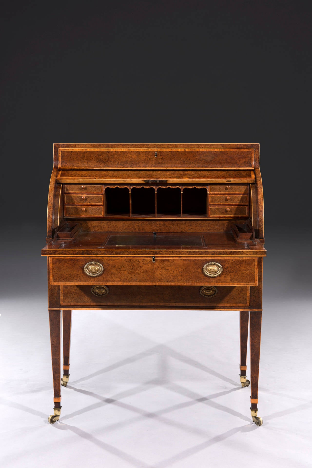 The bureau is very close to a design on pl. 47 of Sheraton's Drawing Book. The roll-top cylinder reveals a yew wood veneered secretaire interior. The top drawer slides out as the top rolls up. The full length drawer below stands on four tapered