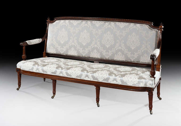 The neo-classsical rosewood frame is fine and crisply carved with John Adam style urns to the back supports and delicately carved rosettes and downward swept upholstered arms with acanthus leaf carving. The bow-fronted seat has upturned leaf carving