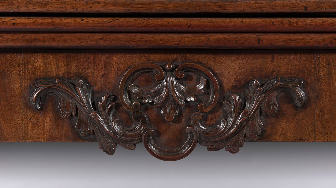 The mahogany cross-banded rectangular top with a flamed mahogany veneer opens up to reveal a tea-table with book-matched veneers with the third leaf revealing a baized gaming surface. The crisply carved mahogany decoration to the frieze is a rare