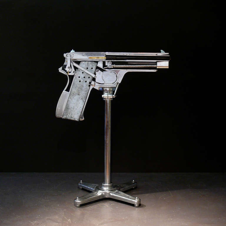 A spectacular large scale cutaway model of a Browning hi-power pistol. This pistol is made from polished steel and aluminium alloys mounted on a heavy steel stand and was used in military training, to show the workings of the gun. The sheer scale of