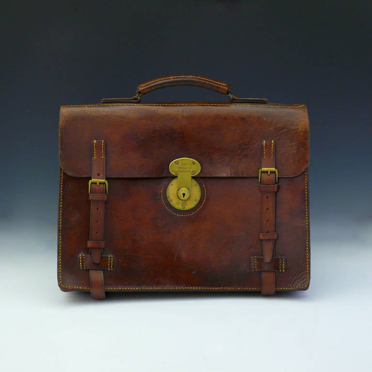 A stylish and beautifully patinated leather flap over briefcase of exceptional quality with original handle and cast brass lock. Our Master Saddler has replaced the straps and gussets by hand and perfectly matched the original construction. It makes