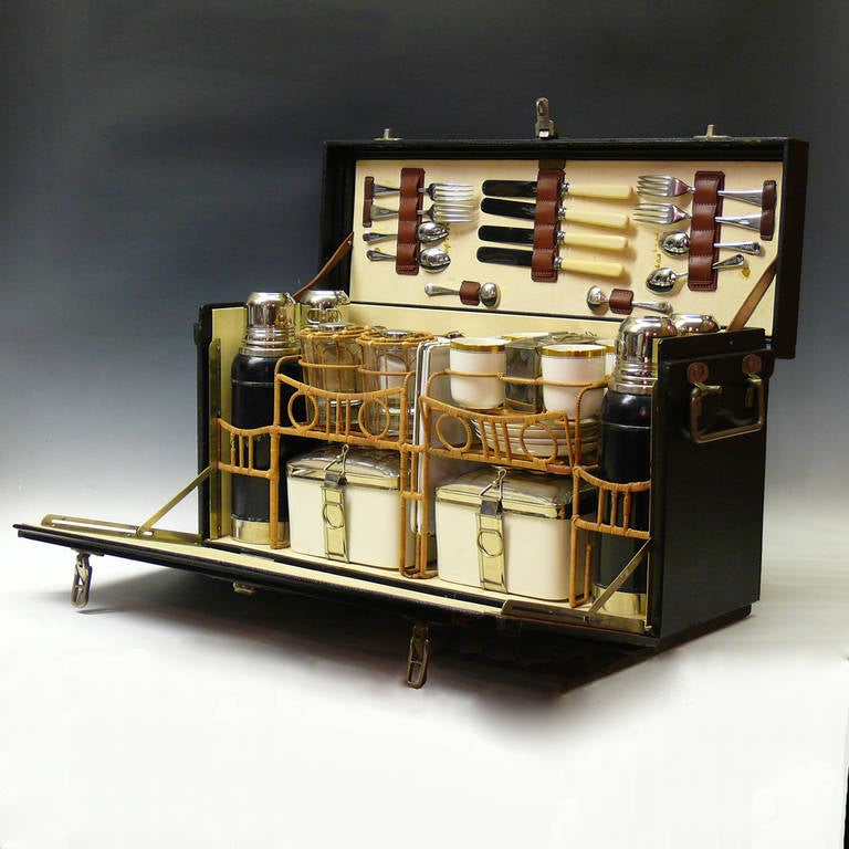 An wonderful vintage picnic hamper made by Coracle for Abercrombie & Fitch. Circa 1930. The set comprises: knives and forks for four people, teaspoons for four people, two cruet spoons, four thermos flasks, four drinks glasses, four enamelled