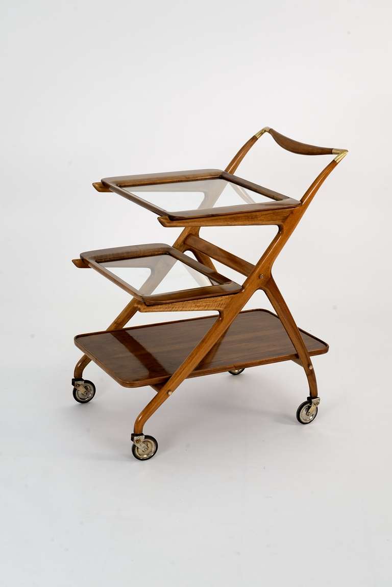 Elegant cart manufactured in Italy in the '50s which strongly reminds the works of Ico Parisi. Rosewood, glass and brass structure with removable trays and exquisite handle decorated with brass elements.