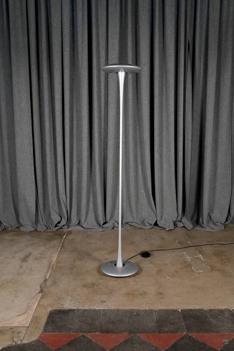 Helice floor lamp designed by Marc Newson for Flos in 1992. Enameled aluminium base, blue crystal diffuser which projects a colored light beam both above and below.