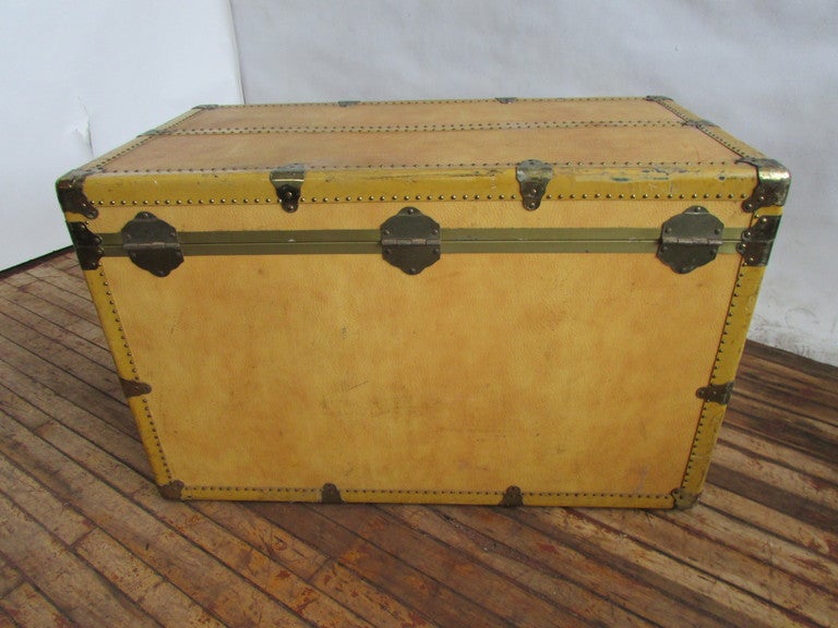 This very handsome old trunk was manufactured by Ventura Travelware - New York, NY. Soft golden yellow vellum like color to grained faux leather body of trunk, genuine leather handles at both sides, brass locks, fittings and decorative tacking. The