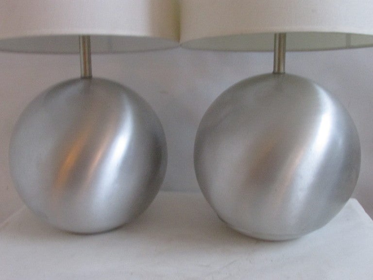 A hard to find pair of mid 20th century american modernist spun aluminum very large round ball lamps often attributed to Russel Wright.  Height listed of 21 inches is to the top of the aluminum rod. Shades are for display purpose only.