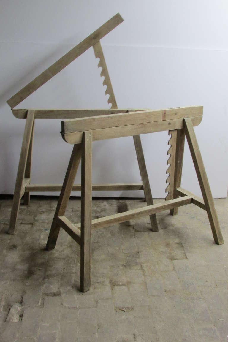 A rare pair of antique woodworker draftsman sawhorses with early pegged construction and top hinged boards mounted with toothed wood planks that lock into a concealed metal bar to change the angles of the work surface ( seven different positions )