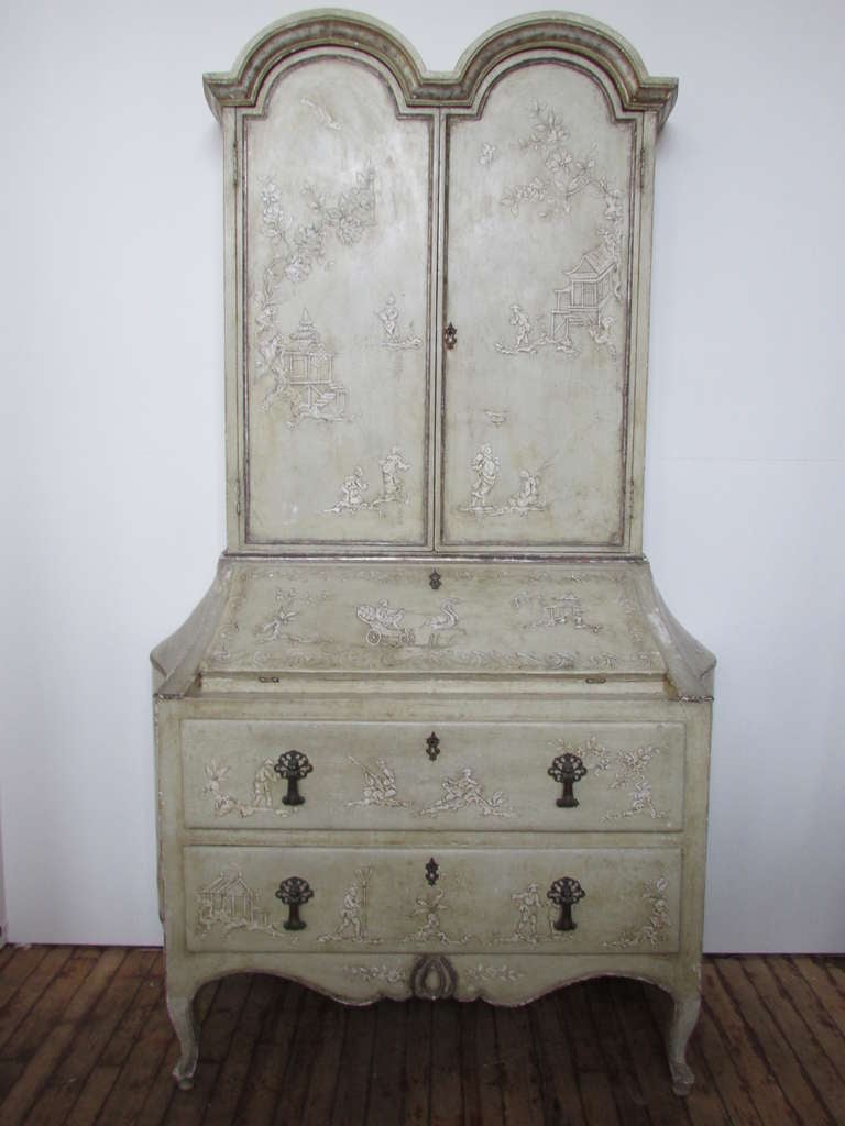 An Italian Venetion secretary in the 18th century style. All original with the most beautifully aged soft pale green painted, silver gold gilded and overall raised scenic chinoiserie decoration. Configuration is an upper arched top two door bookcase