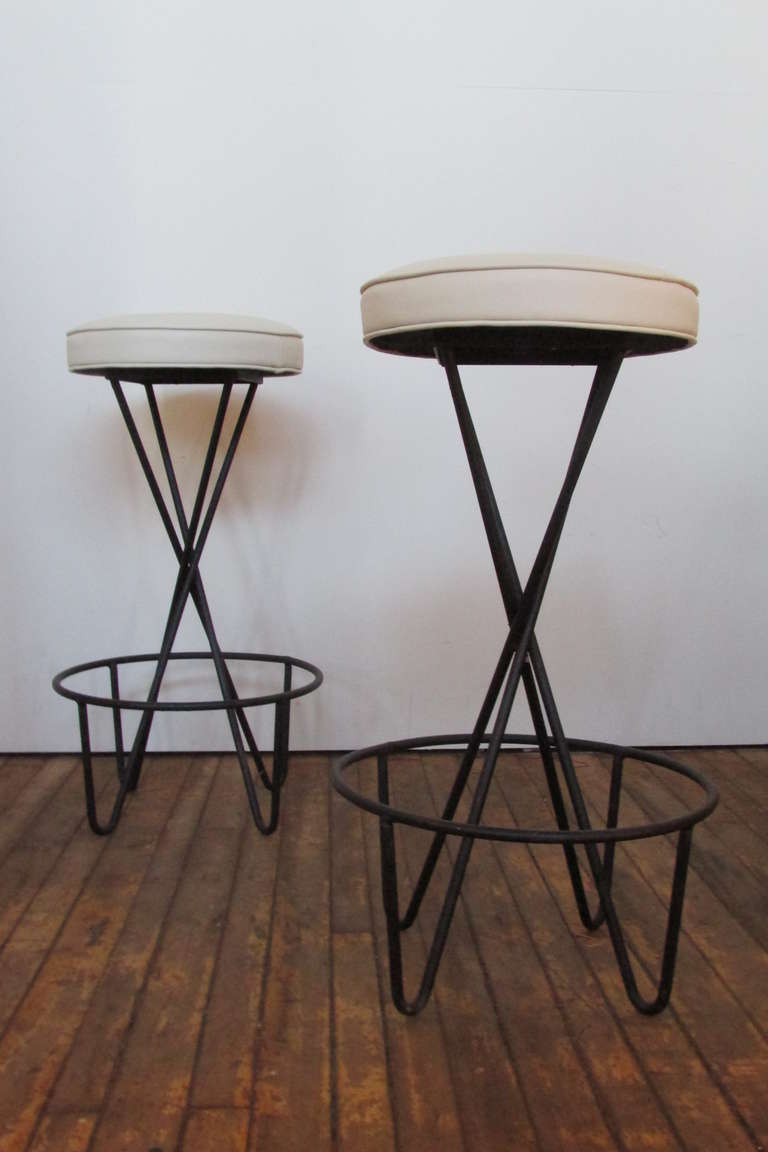 A set of four mid 20th century sculptural black iron hairpin base bar stools by Paul Tuttle - the original seats newly reupholstered in a high quality Architex International lightly textured soft vanilla white vinyl.