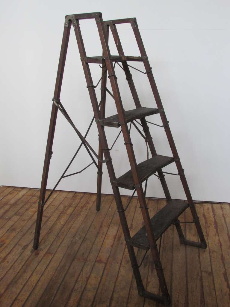 Early folding collapsible ladder. Remnant of original paper label on top step. Beautifully aged patina and color to wood and metal from many years of use. Structurally strong and stable with all fittings present. A striking architecturally