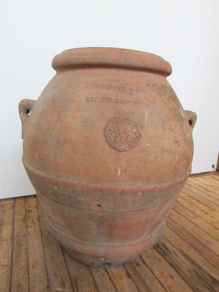 Massive bulbous form Italian terracotta olive oil jar. Stamped GIUSEPPEE FIGLI - RICCERI IMPRUNETA ( Tuscany ) Beautifully aged patina and color to heavy thick walled and well detailed terracotta. This was one of a number of large antique italian