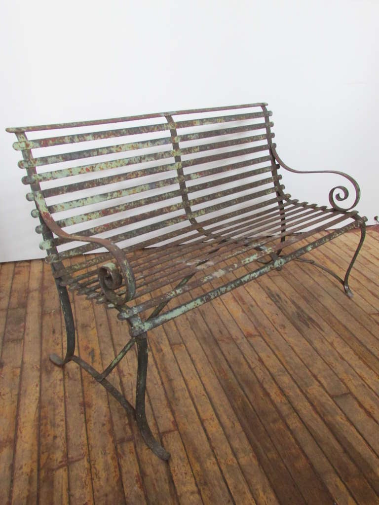 Antique strap iron curule arm garden bench with an elegantly shaped profile. The best naturally aged patina & surface color with traces of the original old paint. Early riveted construction & good quality hand wrought metalwork. We think this is
