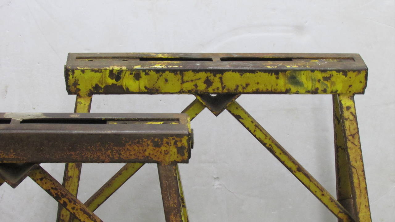 From a long closed local factory an unusual pair of antique industrial iron sawhorses in original aged worn brilliant yellow enamel painted surface. Great looking from every angle - heavyweight and structurally perfect