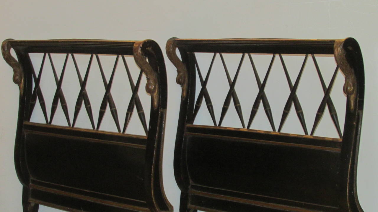 A pair of 1940s classical Regency style sleigh form wood headboards with original ebonized finish and finely carved raised gilded decoration, both top outer posts with curvaceous giltwood swan heads.