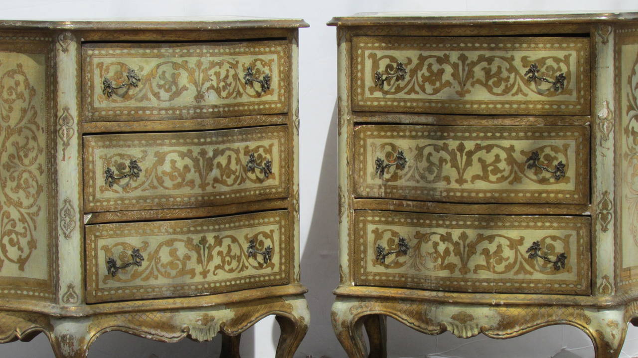 A pair of 18th century style Italian Florentine Venetian three-drawer serpentine form commodes in the original aged gilt decorated and creamy white glaze painted over gessoed surface. The cases each raised on four carved cabriole legs and the