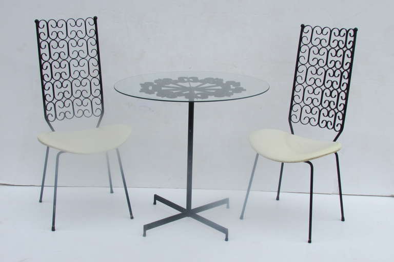 A three piece Grenada Collection bistro set of two tall iron ribbon back chairs and accompanying table by Arthur Umanoff for Shaver Howard - this set first manufactured by Boyuer Scott in 1964 prior to Shaver Howard purchasing the company in 1968. A