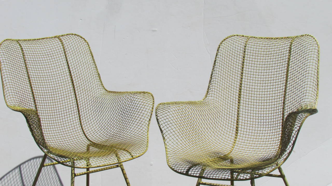 A set of four woodard sculptura high back armchairs in beautifully aged soft chartreuse yellow painted surface, circa 1950s.