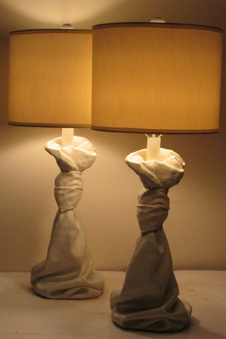 In the style of John Dickinson - a mid 20th century pair of soft white painted solid plaster surrealistic drape form table lamps with the original wood ball finials.