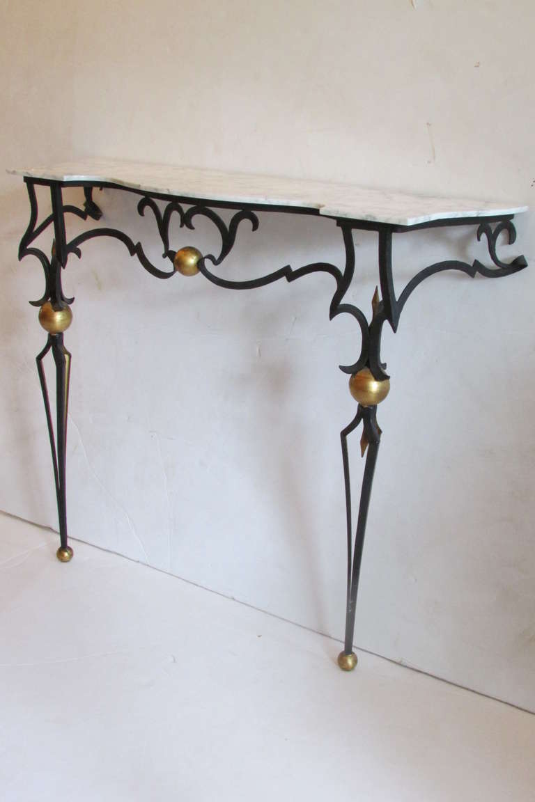 A black forged iron & gilded metal wall mount console and mirror in the style of Gilbert Poillerat. Made in Italy by Palladio dating from the mid 20th century. The console with original marble top / the wall mirror with original plate glass / the