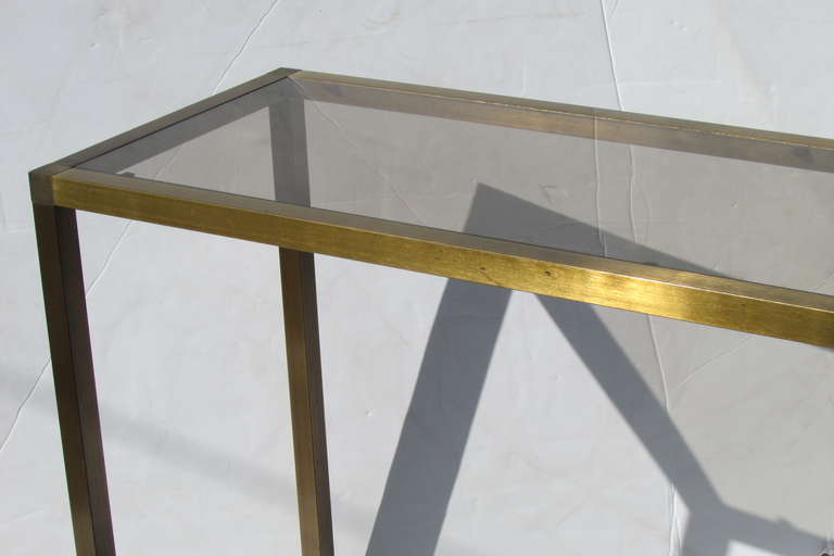 A perfectly proportioned minimalist designed lacquered brass console table or sofa table or server, with beautifully aged rich gold bronze patina color to metal ware. The top with the original lightly tinted inset glass.