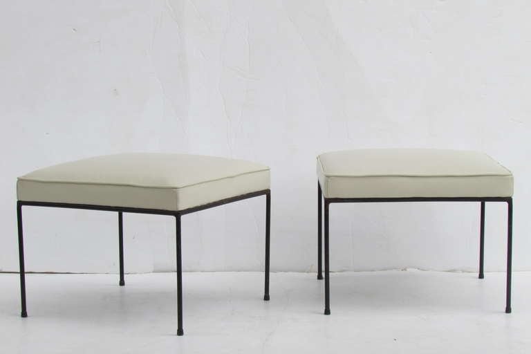 Four Paul McCobb black iron stools / benches / ottomans - newly upholstered in a high quality cream white leather.