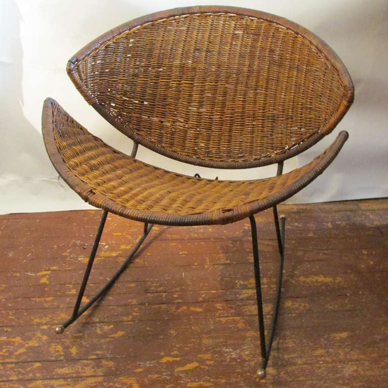 Mid 20th Century modernist natural wicker and steel rocking chair. A well conceived sculptural design form with just the right use of negative space between the curved crescent shaped back and seat as well as the architecture of the iron framework -