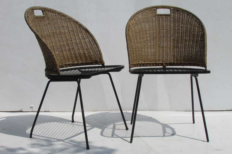 A pair of signed Salterini iron & natural wicker chairs with a pure modern sculptural form.