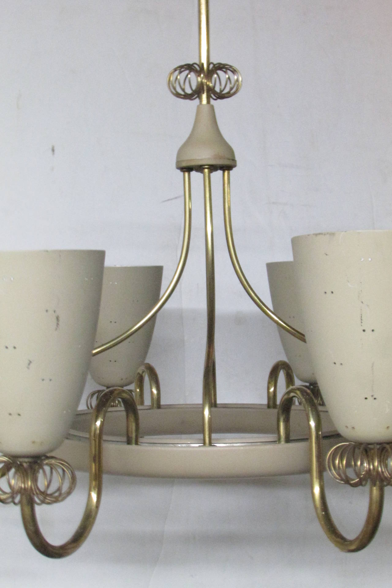 An eight-arm chandelier by Lightolier (stamped on inside metal ring - Canada) in original dry cream white enamel painted metal and brass. Measures 26 inches across by 17 inches high to central brass spiral decoration and approximately 32 inches high
