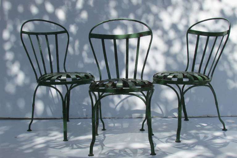 Three matching early 20th century french iron spring pinwheel / sunburst seat garden chairs by Francois Carre in old worn forest green painted surface with some areas of light rust and underlying earlier oxblood & pale green gray paint  showing