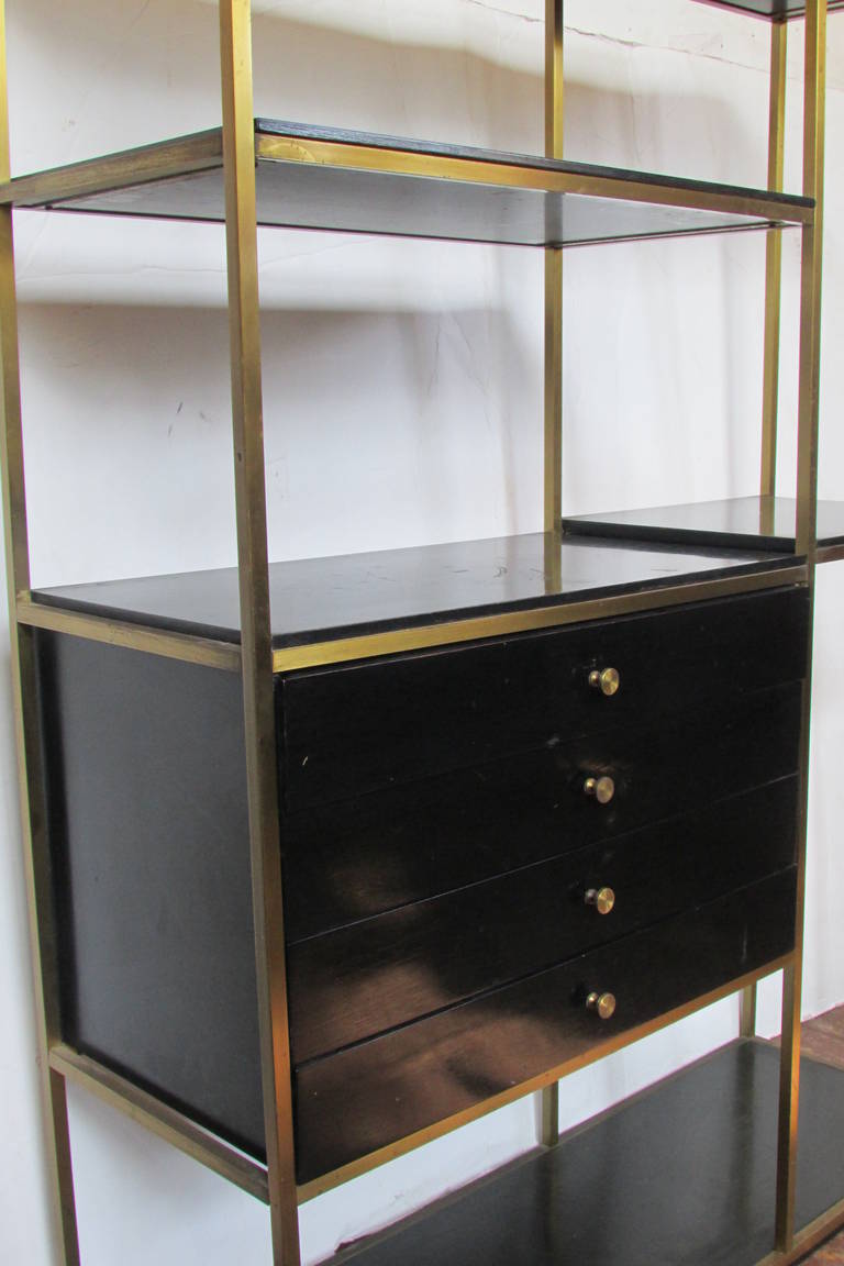 In the style of Paul McCobb - a lacquered brass & black lacquered wood free standing shelving unit with four set drawers.  Designed by Robert Fellner & Mark J. Furst for Furnette - circa 1950's.