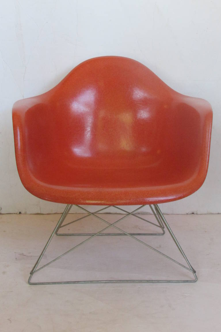LAR chair with original cats cradle base by Eames for Herman Miller, the glowing red orange fiberglass shell with well exposed fiber content. Great condition, circa 1950-1960.